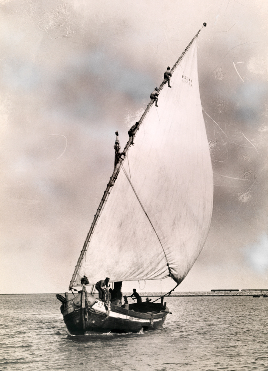 Men climb the mast of a fishing boat to furl the sail in Port Said, Egypt, 1924. Photograph by Maynard Owen Williams, National Geographic Creative
